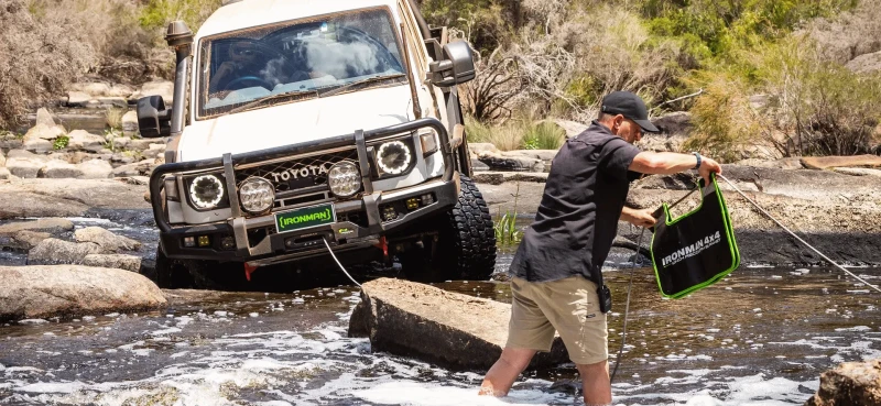 Toyota Landcruiser getting winched out of a river